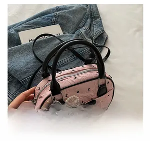Pink crossbody bag featuring black bow patterns and elegant pearl bow charm detail