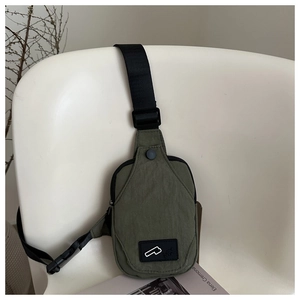 Detailed close-up of olive green crossbody bag with black buckle on a white chair