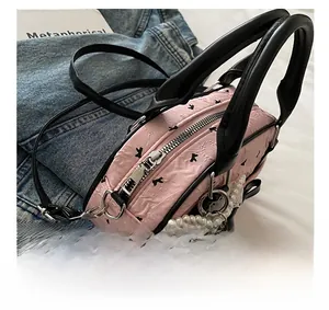 Close-up of pink pleated mini handbag featuring black bow patterns and pearl lace charm