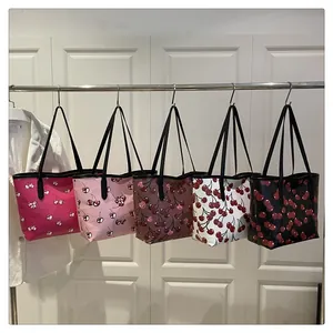 Row of cherry print tote bags in five colors hanging on a display rack for selection