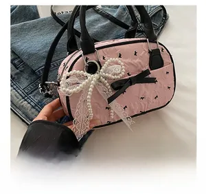 Detail of pink pleated mini handbag featuring black bows and large pearl lace charm