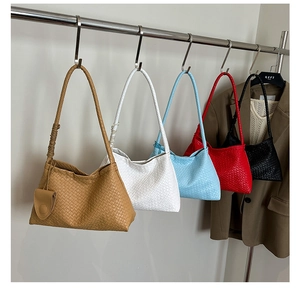 Multiple woven faux leather shoulder bags in various colors on metal hangers