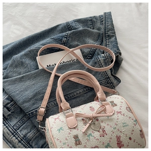 Détail du sac polochon jacquard avec poignées roses et pendentif coeur en métal