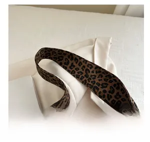 Detailed close-up of high-quality leopard print handbag strap with woven canvas texture