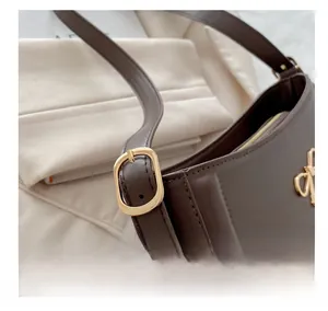 Detail view of the adjustable golden metal buckle on a coffee brown leather bag strap