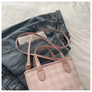 Detail shot of a pink gingham fabric handbag on a denim jacket and white fabric