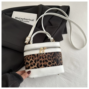 Detail of leopard print bucket bag with white leather trim and gold zippers on blazer
