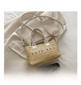 Top view of woven tote bag with TOTE BAG embroidery and leather straps next to a phone