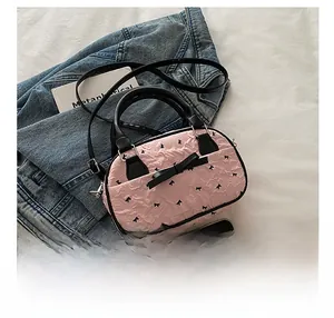 Detailed top view of pink ruffled Boston bag with black bows and detachable strap