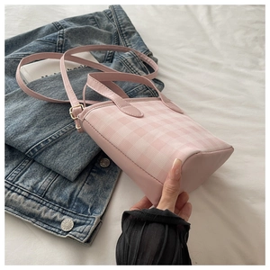 Detail of pink plaid handbag with adjustable strap on white cloth and denim jacket