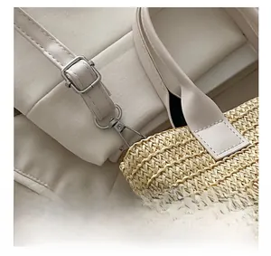 Detail of adjustable leather strap and golden hardware on the woven straw tote bag