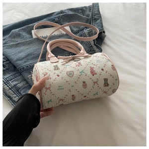 Détail du sac tonneau crème avec des nœuds roses et des motifs d'oursons aux fraises