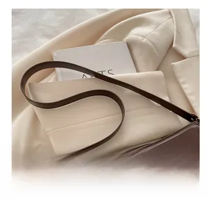 Detail of dark brown leather handbag with gold bow hardware on a cream blazer