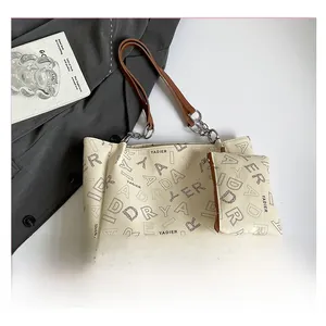 Top view of a beige tote bag set with black letter prints and brown leather handles