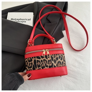 Detail of red leather and leopard print bucket bag with gold zippers and hardware