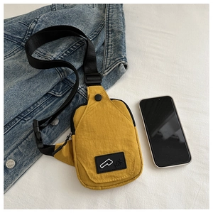 Detail of yellow nylon crossbody chest bag with adjustable black strap and logo patch
