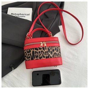 Detailed view of red leather and leopard print bucket bag with gold zipper and hardware