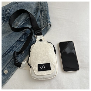 Detail of white nylon crossbody bag with rubber logo, denim jacket and smartphone