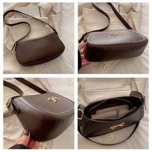 Detailed interior of dark brown leather shoulder bag with gold bow clasp and compartments