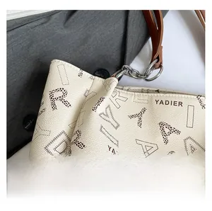 Detail shot of cream tote bag with litchi texture leather and silver chain strap