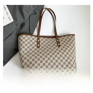 Detail of printed tote bag featuring brown leather handles and gold metal rivets
