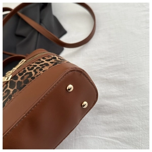 Detail of leopard print bucket bag featuring golden metal protective base studs