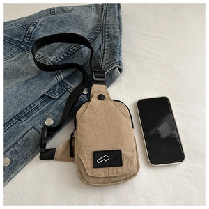 Beige canvas sling bag size comparison with smartphone on blue denim background
