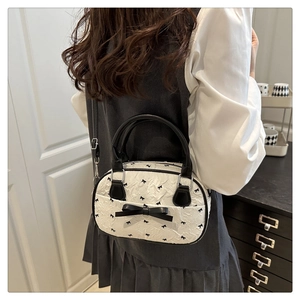 Detail showing white pleated handbag with black bow prints and silver metallic hardware