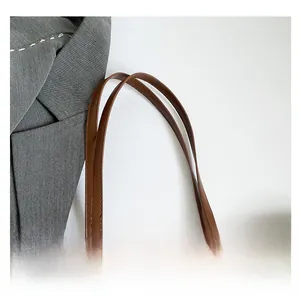Detail of premium brown leather handle and fine stitching on a vintage checkered tote bag
