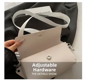 Detail view of the silver magnetic buckle and wide strap on the cream square bag