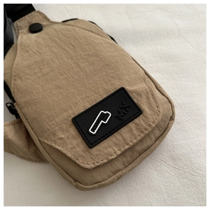 Detail of khaki nylon chest bag showing the textured fabric and MX logo patch