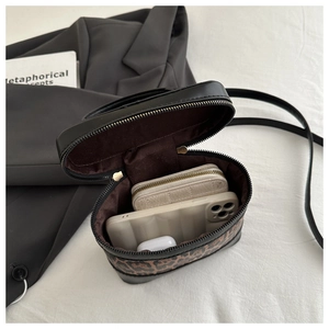 Detailed interior of leopard print bucket bag holding a smartphone and small wallet