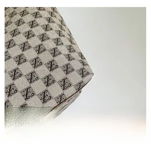 Macro shot of retro jacquard woven fabric with monogram patterns and brown leather piping
