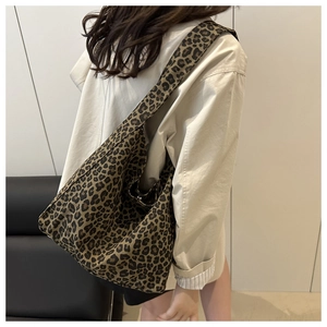 Detailed side view of large leopard print canvas tote bag styled on model shoulder