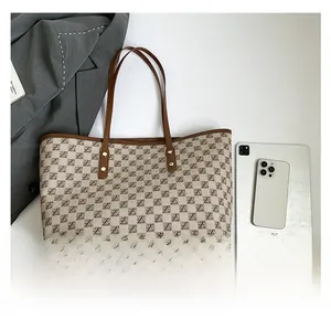 Detailed close-up of a large tote bag with vintage letter patterns and leather trim accents