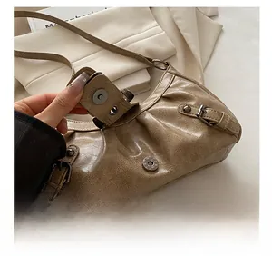 Detailed shot of vintage bronze buckles and magnetic closure on a brown pleated bag