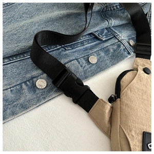 Detail of khaki nylon chest bag showing water-resistant texture and plastic buckle