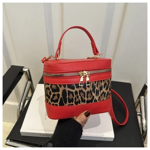 Detail of red leather bucket bag featuring leopard print panel and dual metal zippers