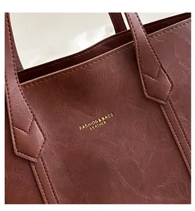 Close-up of vintage brown leather tote bag with gold-tone FASHION & BAGS lettering
