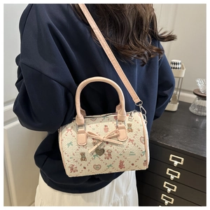 Détail d'un mini sac Boston avec imprimés cartoon, anses en cuir rose et nœud décoratif