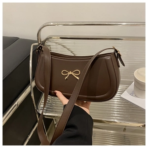Detail of dark brown baguette bag featuring a gold bow metallic buckle and matte finish