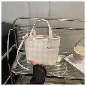 Detail of gingham plaid bucket bag with top handle and adjustable shoulder strap