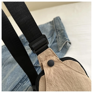 Detailed close-up of the khaki canvas chest bag showing nylon fabric and buckle