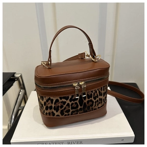 Detail of leopard print bucket bag with brown leather contrast and gold zipper