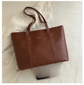 Detail of dark brown tote bag showing lychee grain leather and fashion gold lettering