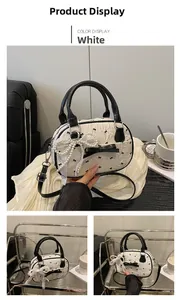 Detail of white textured Boston bag with black bows and decorative pearl lace charm