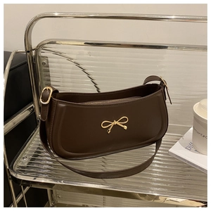 Detail of matte brown shoulder bag with elegant gold bow hardware and zipper closure