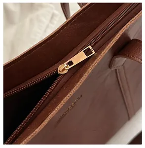 Close-up of smooth golden metal zipper on vintage brown leather tote shoulder bag