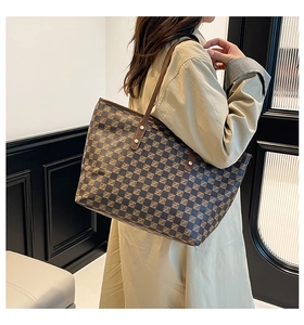 Detail of vintage monogram pattern on tote bag with leather strap and metal studs