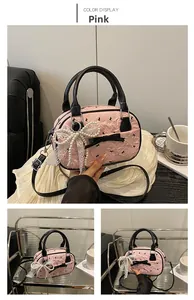 Close-up of pink embossed leather bag with black bow detail and pearl lace pendant
